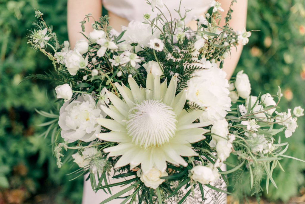 modern bride holding onto a bouquet of white blooms and greenery